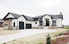 a large white house with two garages on the front and one car door open