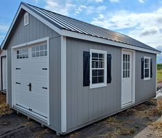 a small gray shed sitting on top of a dirt field