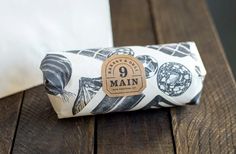 a white and black bag sitting on top of a wooden table next to a pillow