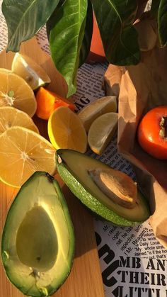 an avocado cut in half next to oranges and lemons