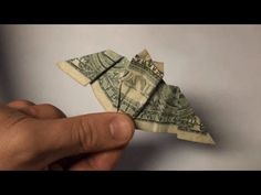 a person is holding an origami bird made out of one dollar bank note