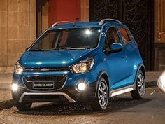 a blue car parked in front of a building at night with its headlights turned on