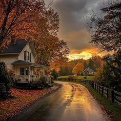 a house on the side of a road with fall foliage around it and trees lining the street