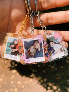 a hand holding a keychain with three pictures on it