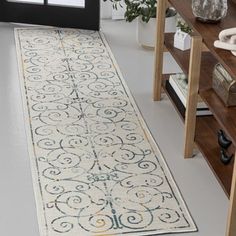 a white and yellow runner rug on the floor in front of a window with potted plants