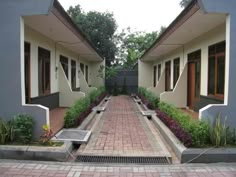 the walkway between two buildings leads to another building with plants and flowers on either side