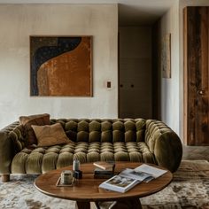 a living room with a couch, coffee table and paintings on the wall behind it