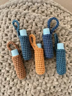 three crocheted bottles sitting on top of a knit mat next to each other