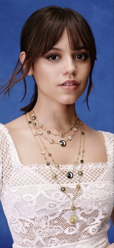 a woman wearing a white dress and some necklaces