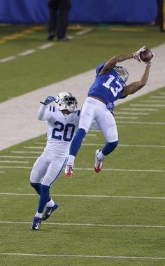 two football players jumping in the air to catch a ball