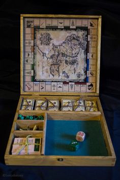 an open wooden box with dices in it and a map on the wall behind it