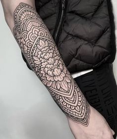 a woman's arm with a tattoo on it, and an intricate design in the middle