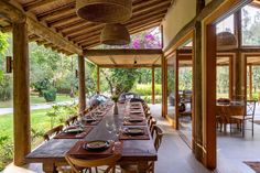 an outdoor dining area with wooden tables and wicker chairs, surrounded by greenery