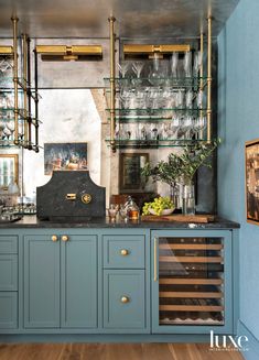 a kitchen with blue cabinets and shelves filled with wine glasses on top of wooden floors