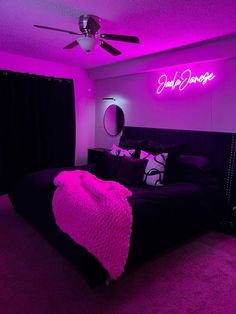 a bedroom with purple lighting and a black bed in the center, along with a pink blanket on top of it