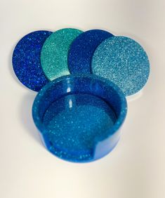 blue and green glittered coasters sitting next to each other on a white surface