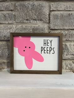 a pink teddy bear with the words hey pees on it in front of a brick wall