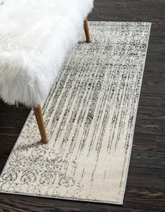 a white bench sitting on top of a wooden floor next to a black and white rug