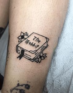 a person with a tattoo on their arm that says the book is in black ink