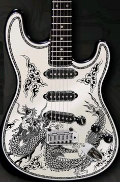 an electric guitar with dragon designs on it's body and neck, sitting against a black background