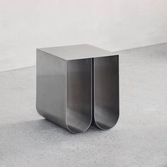 a metal table sitting on top of a cement floor next to a white wall in an empty room