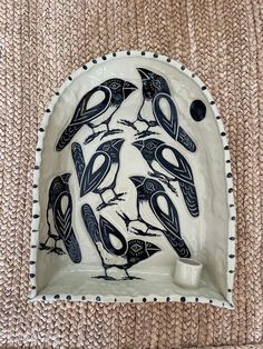 a ceramic dish with birds painted on the front and sides, sitting on a rug