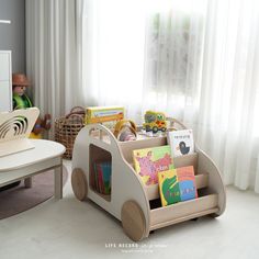 a child's wooden toy car with books in it and toys on the floor