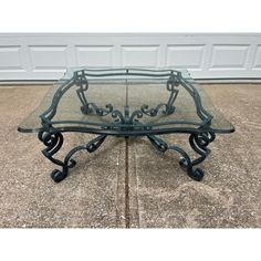 a glass and metal coffee table with wheels on the bottom, sitting in front of a garage door