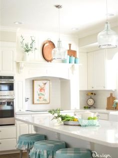 a kitchen with white cabinets and blue stools in front of the counter top area