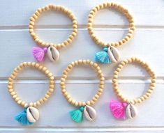 four wooden beads with tassels and seashells are arranged on a white surface