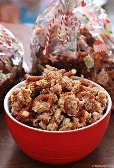 a red bowl filled with nuts next to two bags of candy caned candies