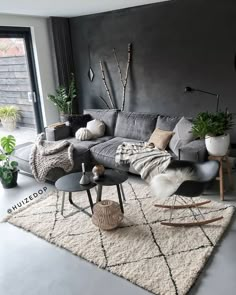 a living room filled with lots of furniture and plants on top of a rug in front of a window