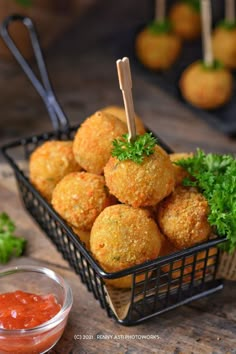 some food is in a black basket on a table with sauces and toothpicks