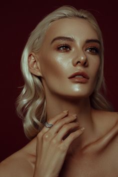 a woman with blonde hair wearing a diamond ring and holding her hand up to her chest