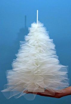 a hand holding a white christmas tree made from tulle