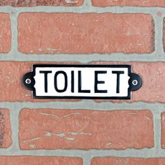 a black and white sign on a brick wall that says tolet in large letters