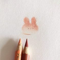 two pencils sitting next to each other on top of a piece of white paper