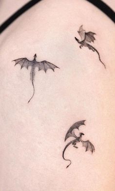 three small dragon tattoos on the back of a woman's left shoulder and chest