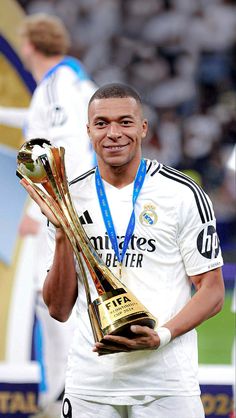 the soccer player is holding two trophies in his hands