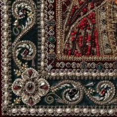 an embroidered cloth with beads, pearls and other things on it's edges is shown in close up