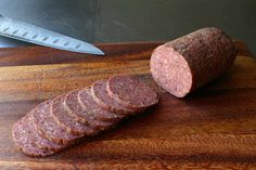 sliced sausage on a cutting board next to a knife