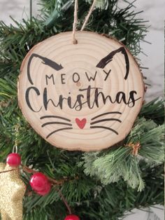 a wooden ornament hanging from a christmas tree with the words meow christmas written on it