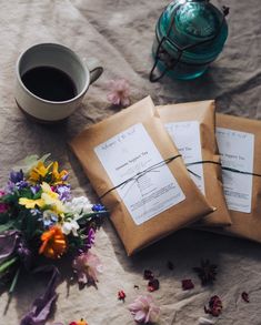 two brown envelopes sitting on top of a table next to a cup of coffee