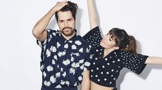 a man and woman standing next to each other in front of a white wall with polka dots on it