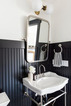 a white sink sitting under a bathroom mirror next to a black and white striped wall