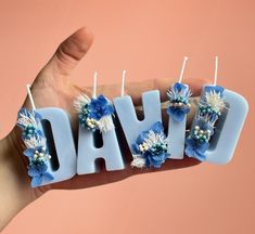 the word david spelled out with blue flowers and pearls on it's sides in front of a pink background