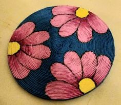 a blue, pink and yellow bowl with flowers on it sitting on a table next to a wall