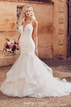 a woman in a wedding dress posing for the camera with her hand on her hip