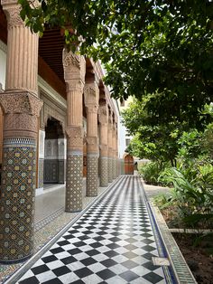 an ornate building with columns and checkered tile on the floor, surrounded by greenery