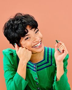 a woman smiling and holding a pen in her hand while wearing a green shirt with blue stripes